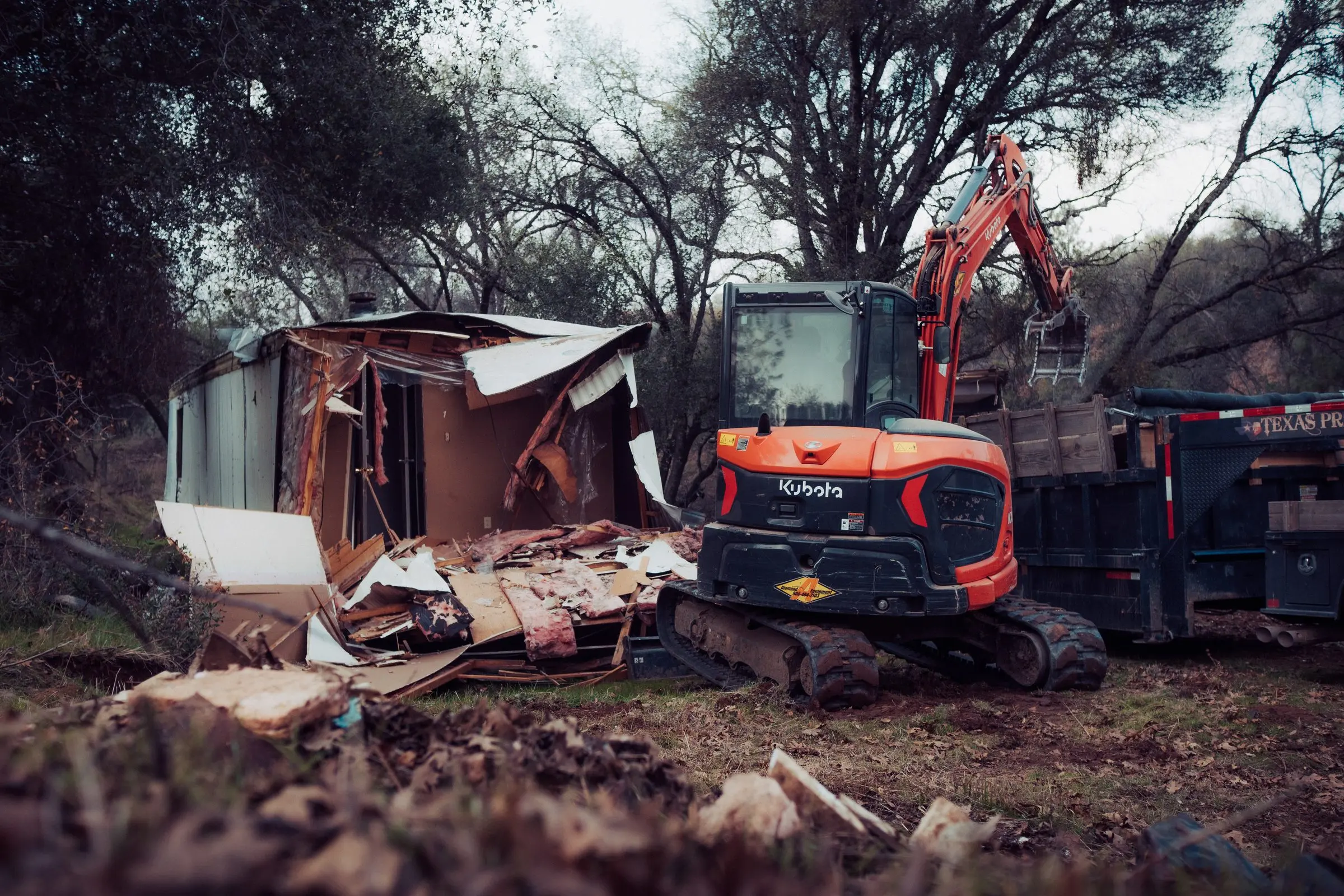 Kubota excavator next to a partly demolished mobile home