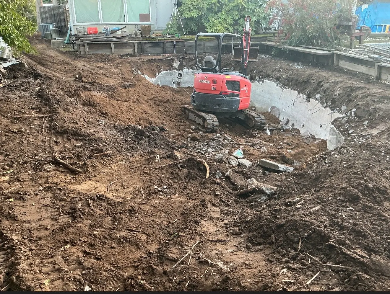 Mini excavator working inside a backyard pool shell