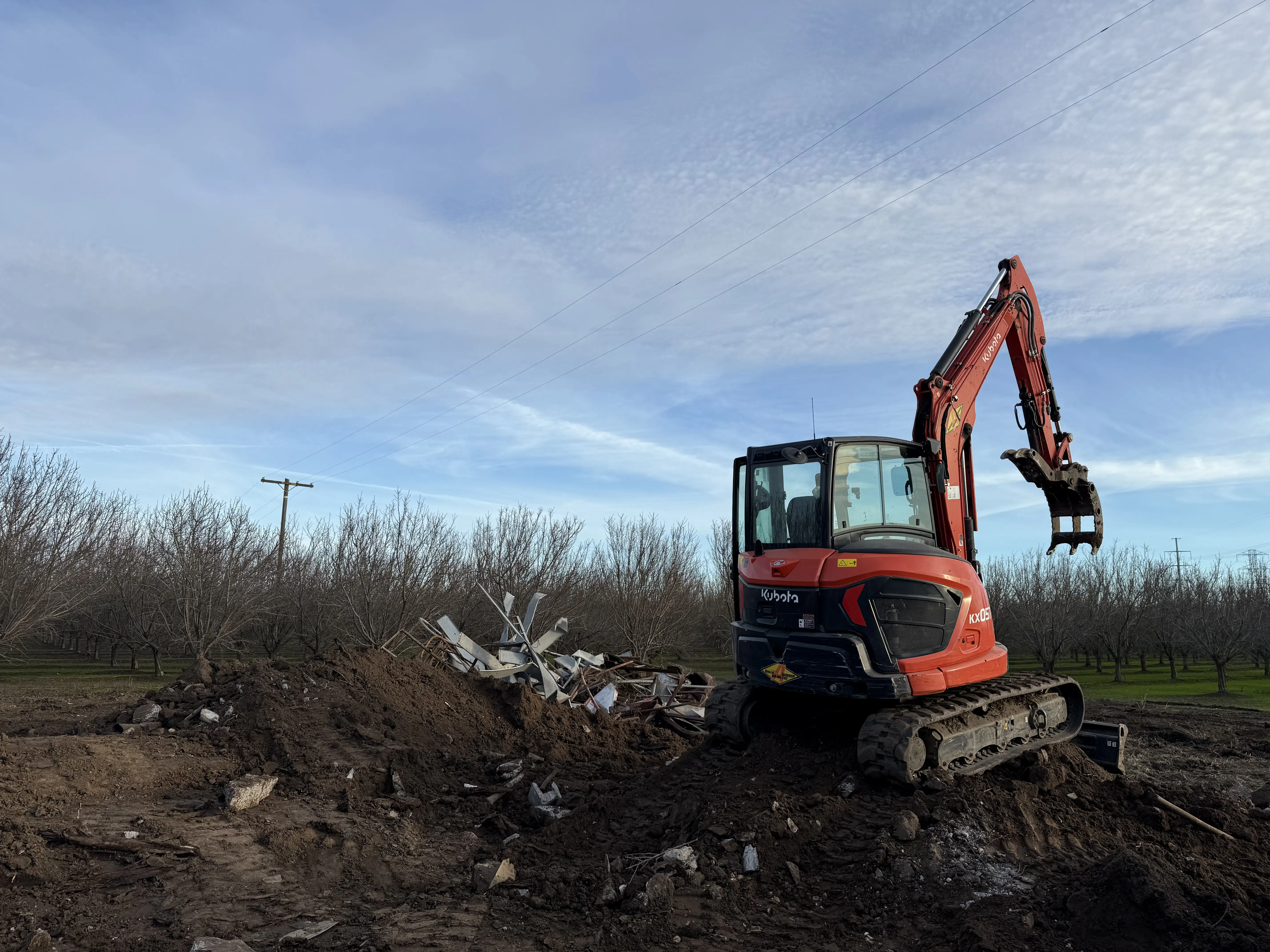Demo Patrol Kubota excavator working a debris pile on a rural teardown site